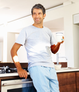 Mature man holding a cup of coffee in his kitchen